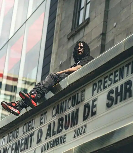 Someone wearing black clothing and red sneakers reclines on an angled surface with French text below.