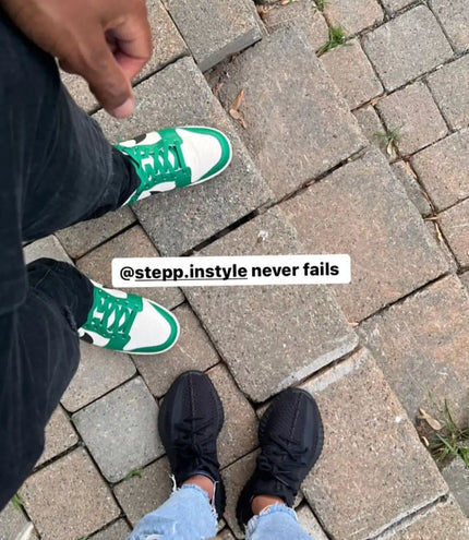 Green sneakers worn by someone standing on a paved surface.