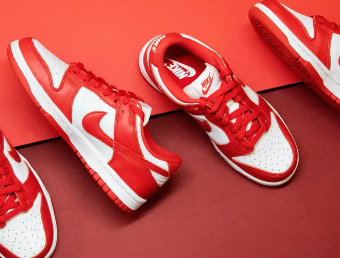 Red and white Nike sneakers arranged on a red surface.