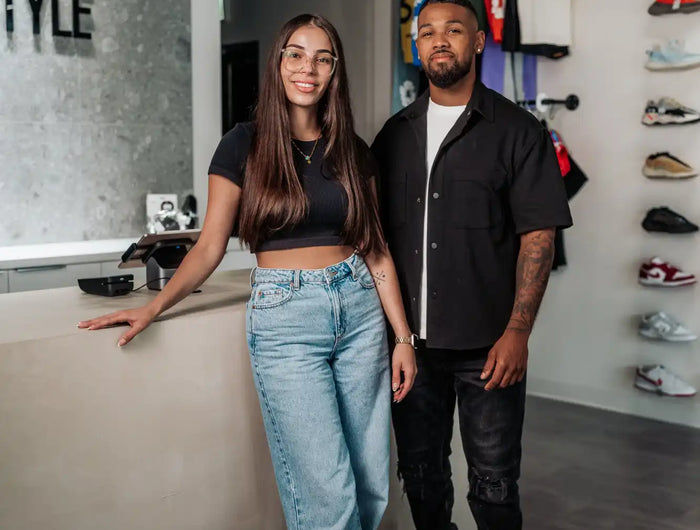 Two people standing together in a clothing and shoe store.