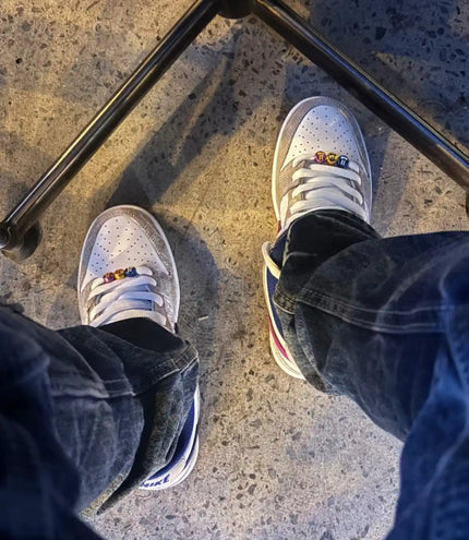 White sneakers worn by someone standing on a textured floor.